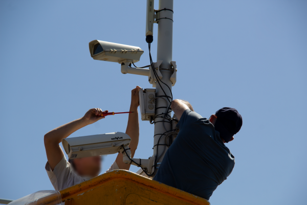 Photo de deux techniciens en train d'installer des caméras sur un poteau